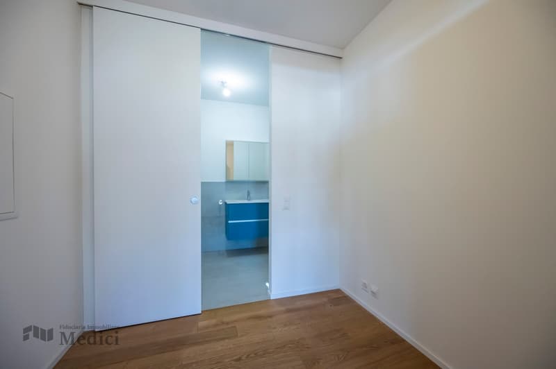 Minimalist room, white walls, wooden floor, glass door, bathroom sink, blue bathroom cabinet