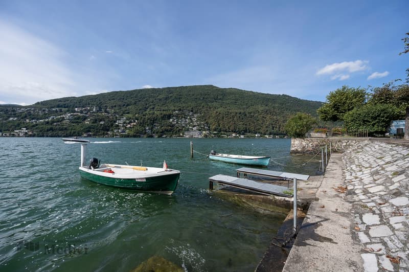 2 boats anchored to pier, lake, mountains in the background