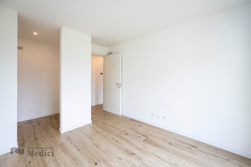 Empty room, hardwood floor, white walls, white ceiling, open door, electrical outlets