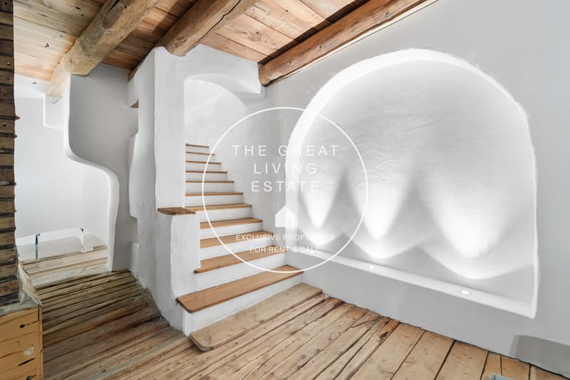 staircase made of wooden steps, walls painted white, arch above the staircase, rustic wooden ceiling