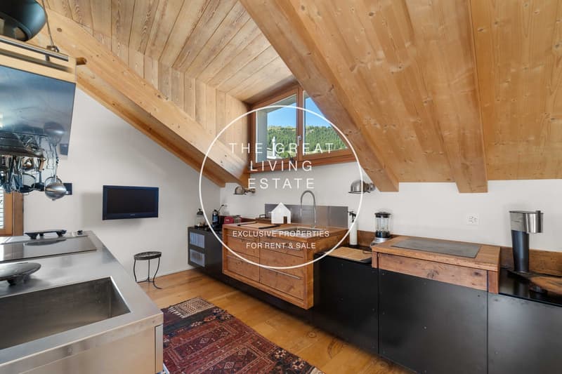 wooden ceiling, wooden flooring, stainless steel countertop, TV mounted on the wall, large window, sink with faucet, rug, dark wooden cabinets