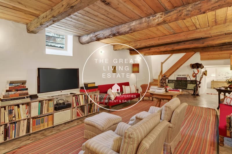 living room, exposed wooden beams, white walls, red couch, bookshelf, TV, rug, lamps, rug
