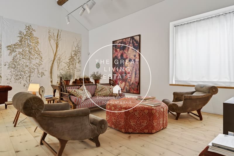 wooden floor, white walls, comfortable seating, artwork, lamps, ottoman, fireplace, window curtain