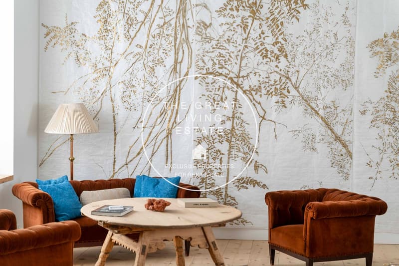 room with brown couches, wooden table, white wall, decorative lamps, gold leaf wall art