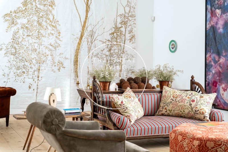 living room, wooden floor, large couch, sofa pillows, table with lamp, stool, brown armchair