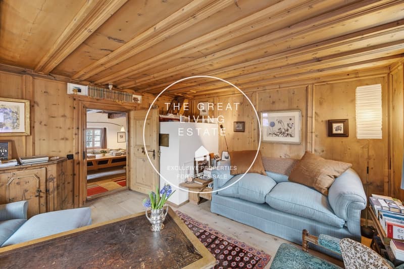 exposed wooden beams, fireplace, sofa, armchairs, wooden coffee table, rug, flower vase