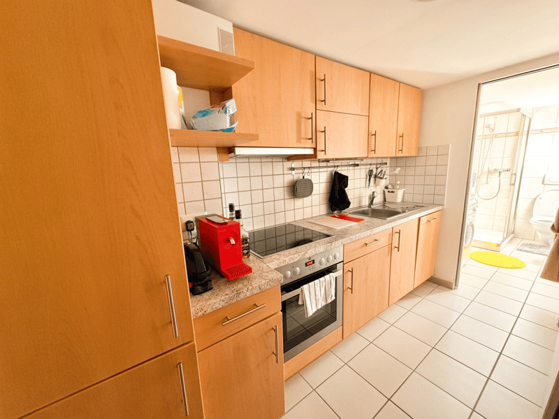 kitchen with wooden cabinets, tiled floor, gas stove, oven, sink, countertop, coffee machine, toaster, towels, washing machine
