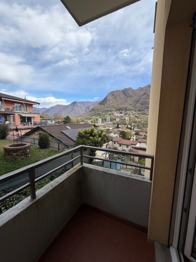 Balcony with metal railing, red floor, view of mountains and houses