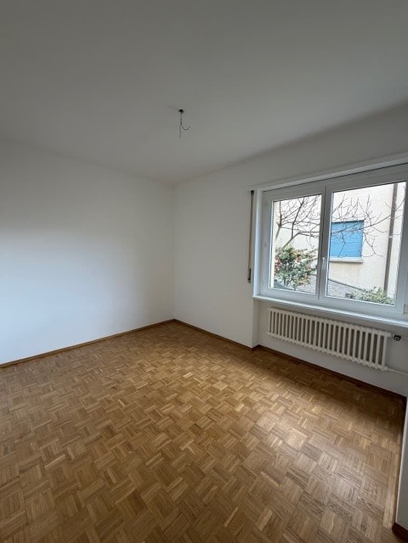 empty room, wooden floor, white walls, large window, white radiator