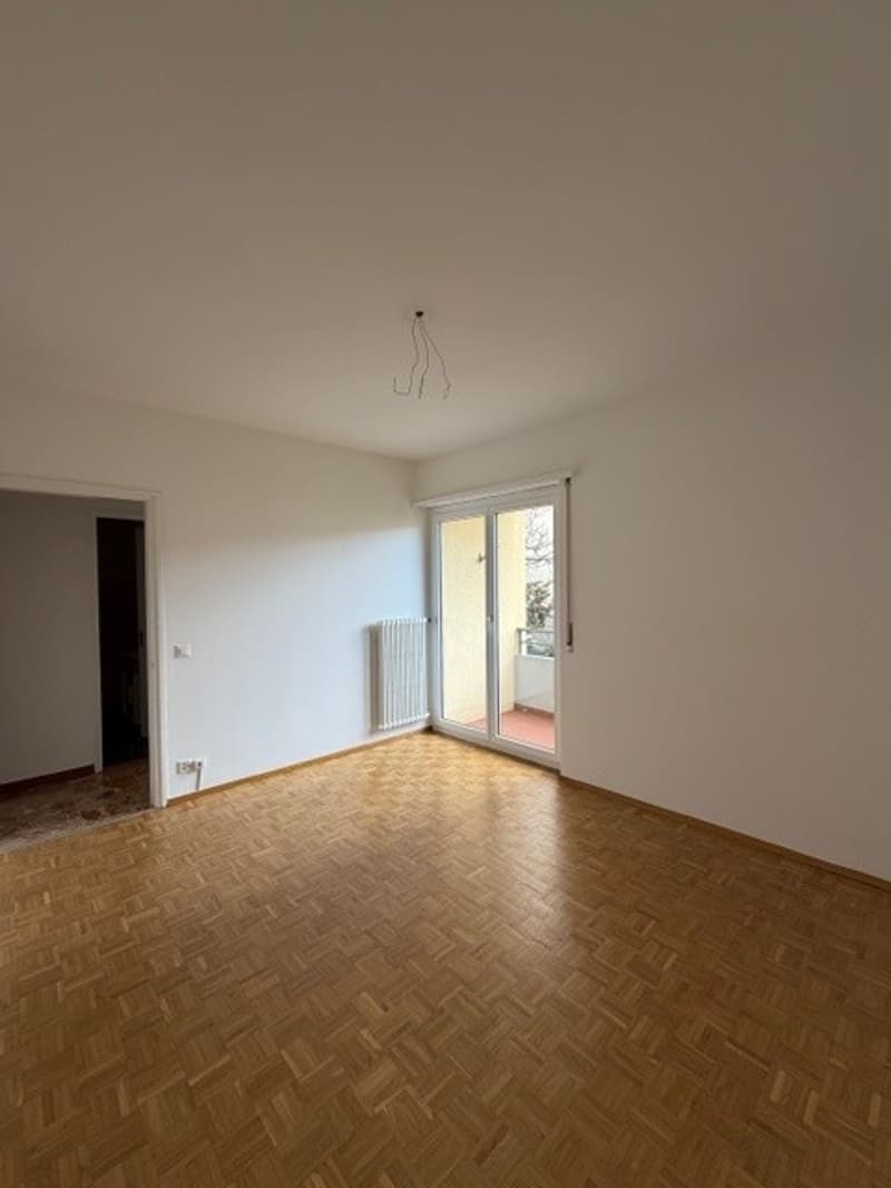 empty room, wooden floor, white walls, sliding glass door, balcony, radiator