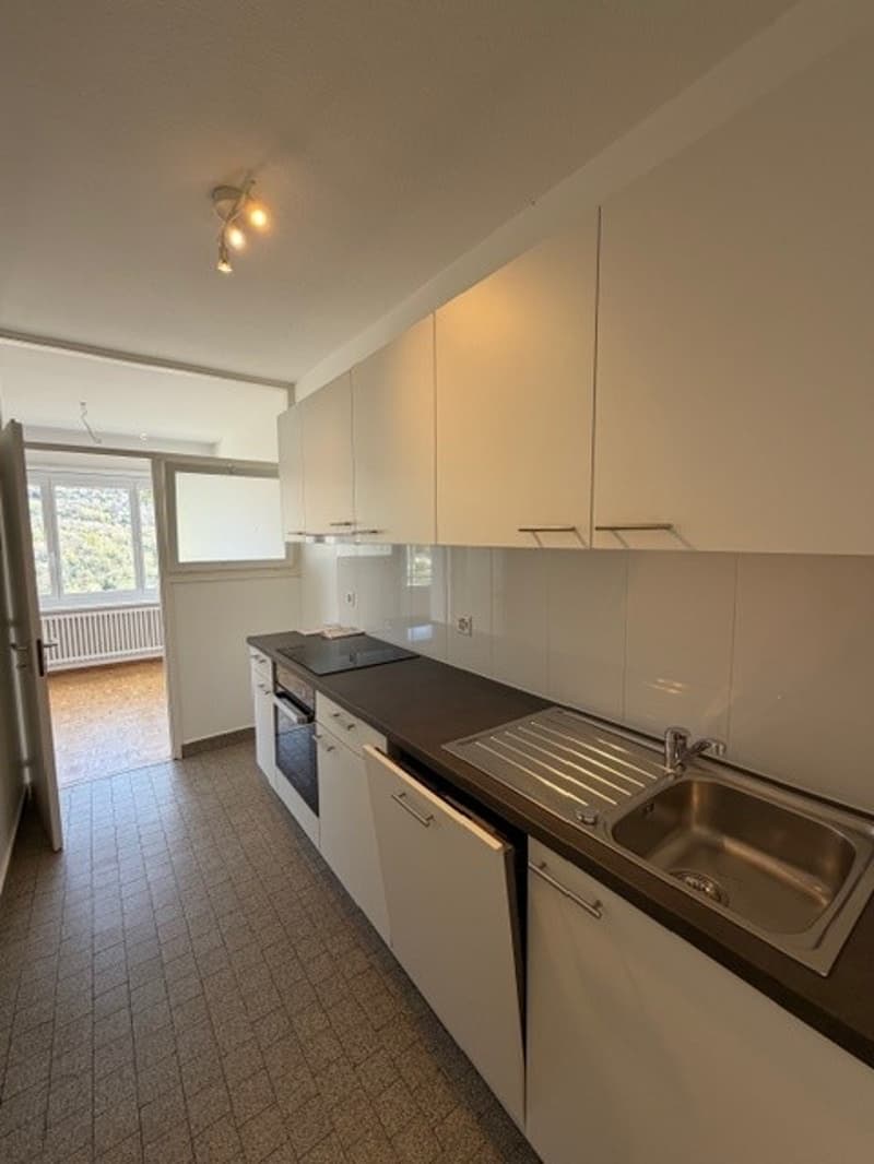 modern kitchen with white cabinets, black countertop, stainless steel sink, dishwasher, and a window