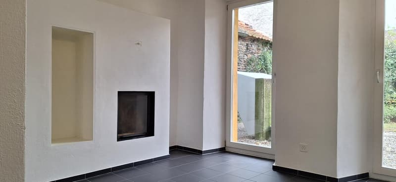 White walls, fireplace, black tile flooring, glass sliding door