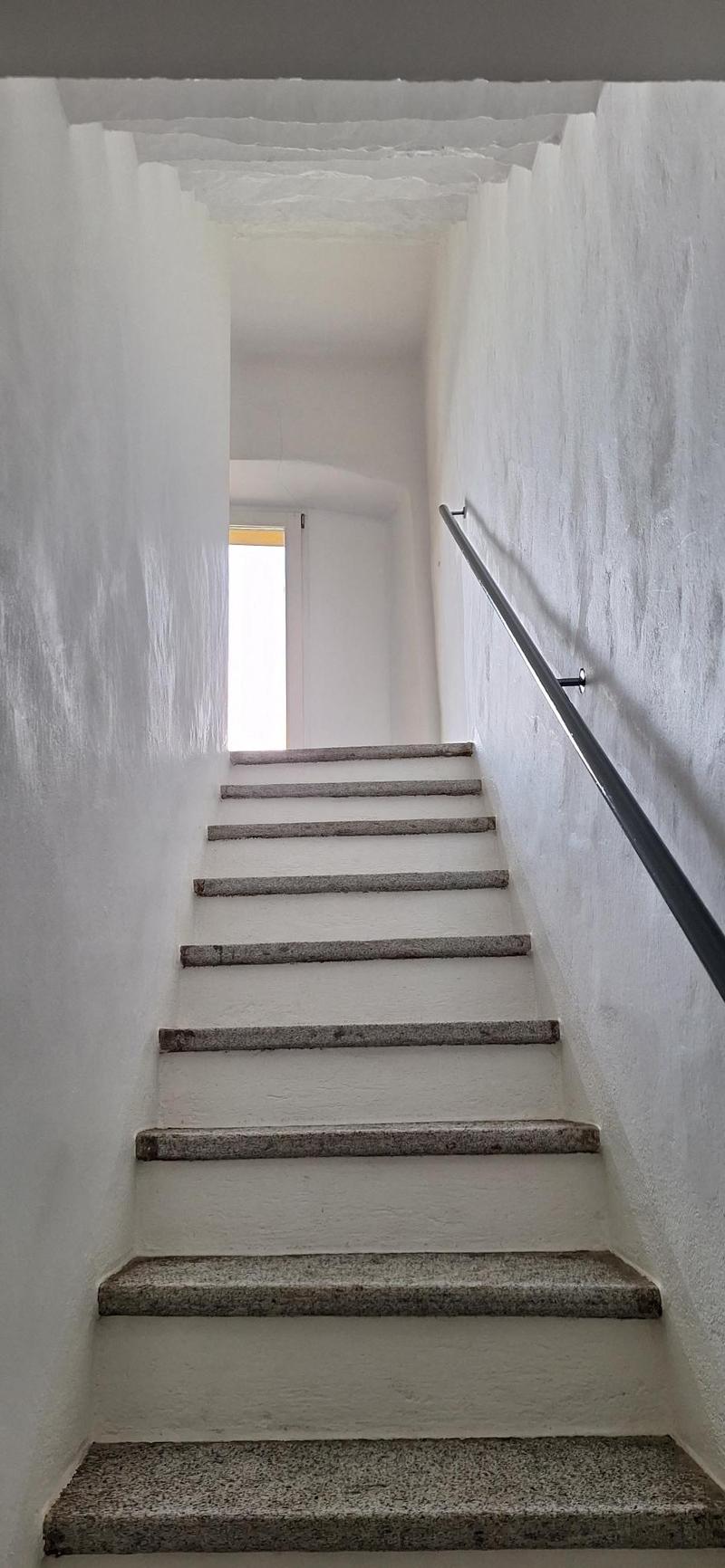concrete stairs with a white wall and handrail