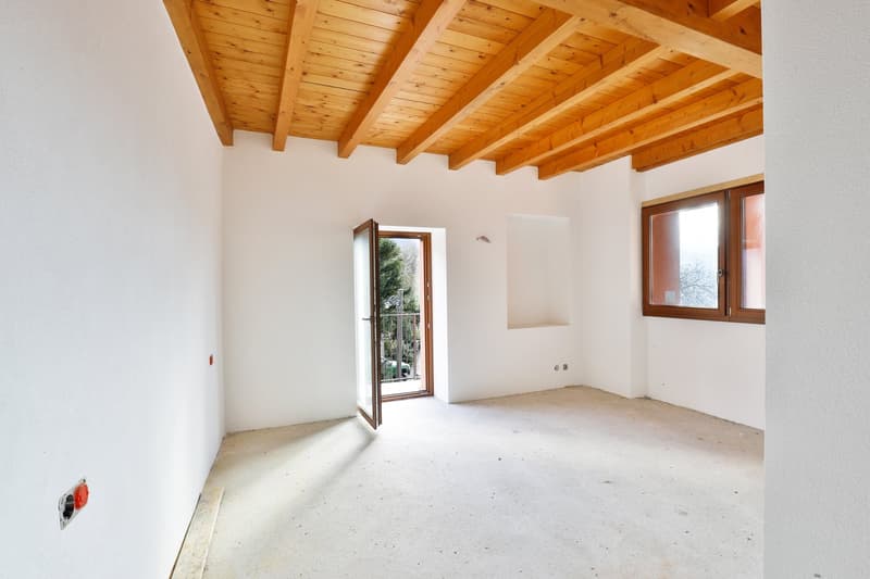 Empty room, wooden ceiling, white walls, open door, window, power outlet.