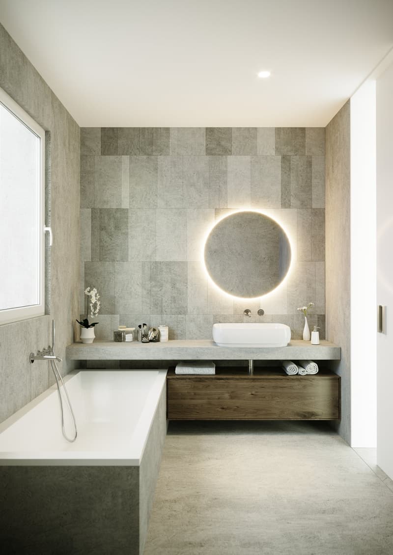 Spacious bathroom with gray tile walls, a freestanding bathtub, a floating vanity with a round backlit mirror, and open shelving for storage.