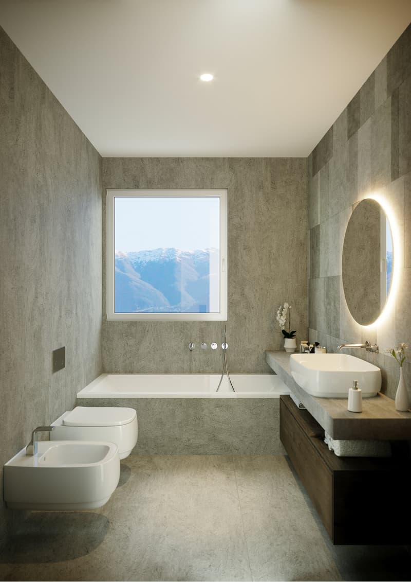 Spacious bathroom with large window offering a scenic mountain view, white bathtub, vanity with sink, and a round illuminated mirror