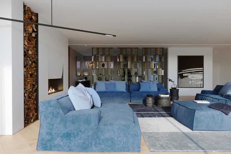 Spacious living room with blue velvet sofas, a fireplace with a stack of firewood, and a modern shelving unit with decorative items. The room has a minimalist and cozy design with neutral colors and textures.