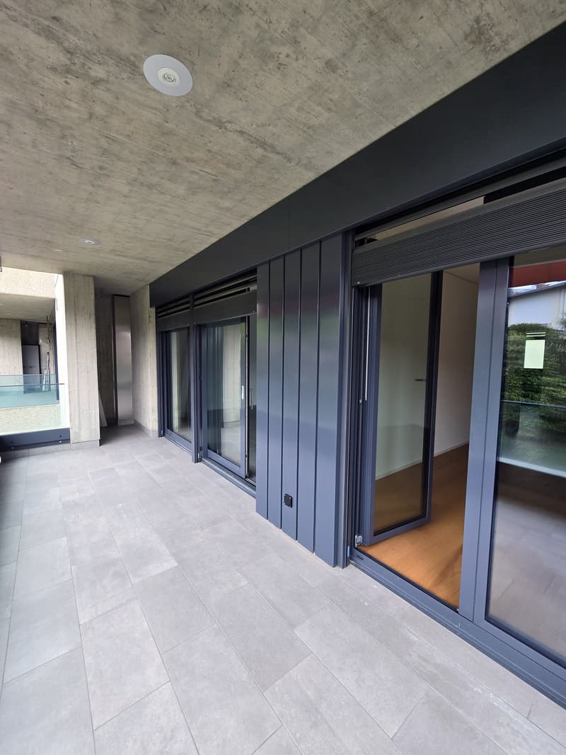 Open space with sliding glass doors, tiled floor, empty room with wooden floor