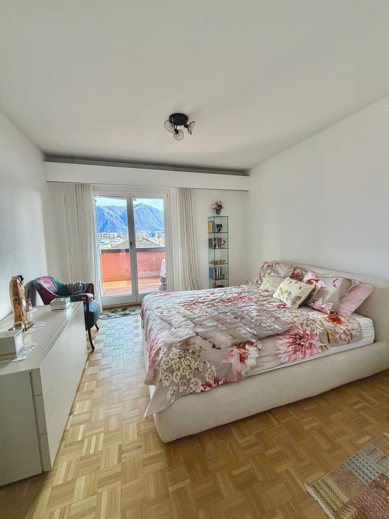 bedroom with a bed, a chair, a cabinet, a shelf, a rug, and a balcony with a view
