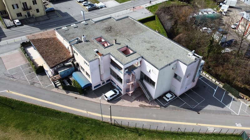 Multi-story commercial building with a flat roof, parking spaces, and landscaping around the property.