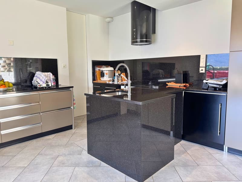 Modern kitchen with black granite countertops, built-in dishwasher, stainless steel appliances, and tile flooring.