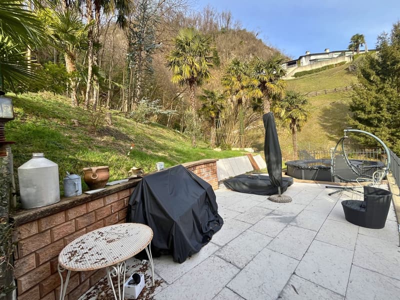 brick paved patio, table, chairs, outdoor jacuzzi, trees, plants, hills, clear sky