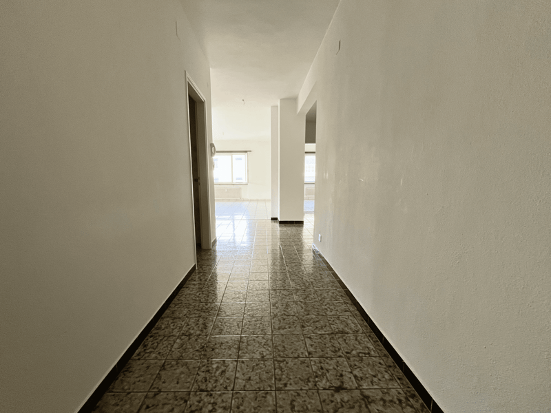 empty hallway, tiled floor, white walls, doorway, windows, and white tiles