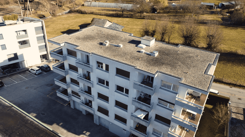 Multi-story residential building, balconies, parking lot, flat roof