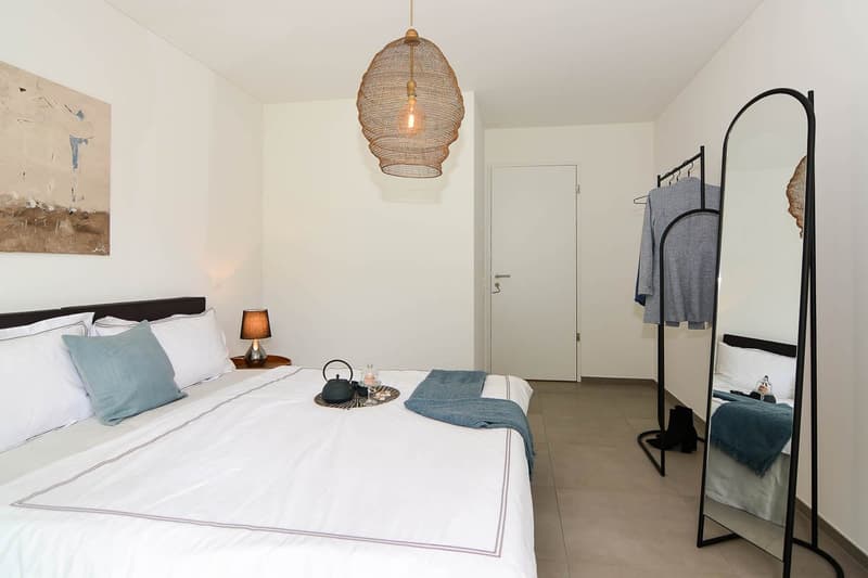 Bedroom with bed, nightstand, lamp, mirror, and artwork on the wall