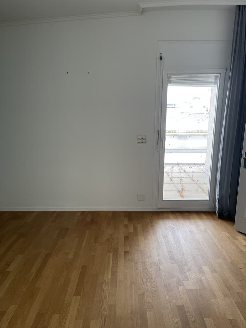 Empty room with white walls, hardwood flooring, and a window with a view of the outdoors.