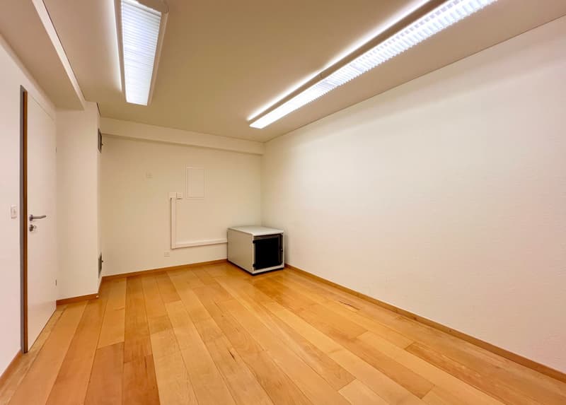 Empty room with hardwood flooring, white walls, and recessed lighting fixtures on the ceiling.