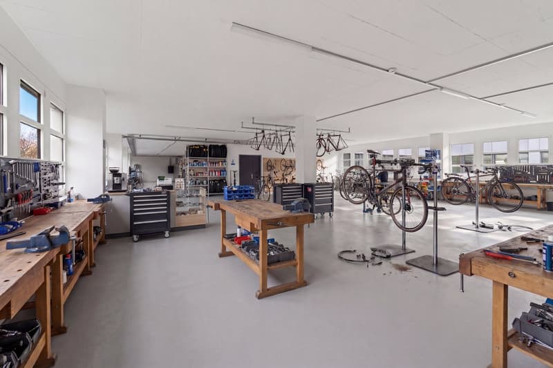 large workshop with workbenches, tools, bicycles, and storage shelves