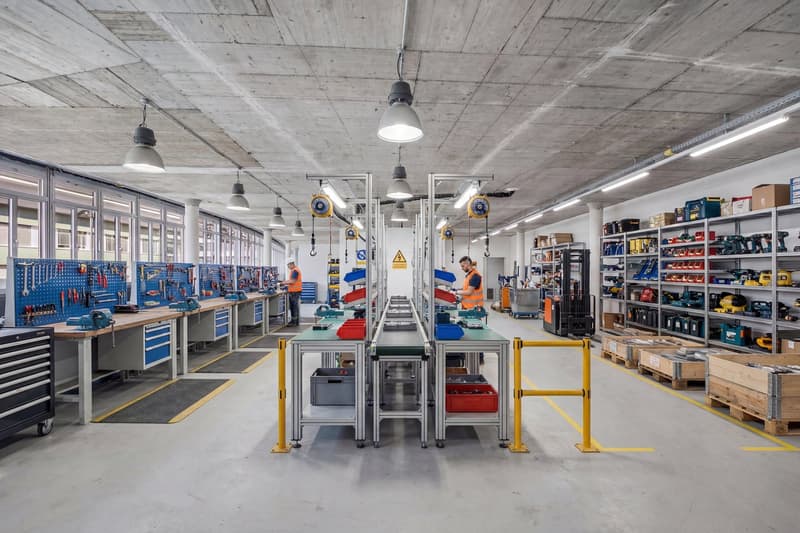 large workshop with multiple workbenches, tools, and machinery