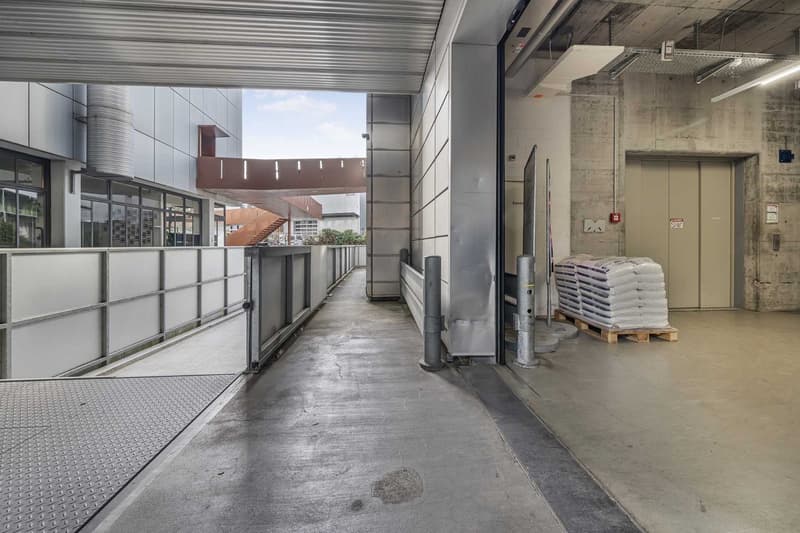 underground parking lot with concrete floor, metal railings, and stack of white bags on the right