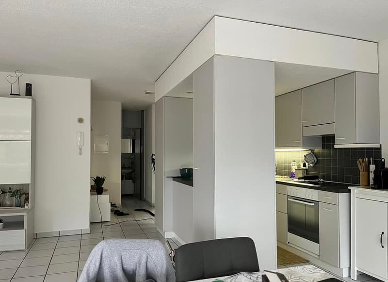 open concept living/dining room with modern, minimalistic design, white walls, tiled floor, and an integrated kitchen