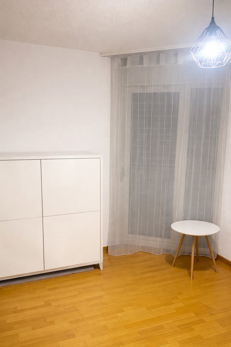 wooden floor, white curtain, white cabinet, small round table