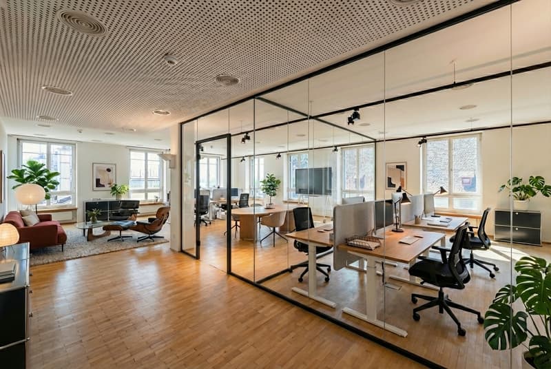 modern office space with glass walls, wooden floors, several tables and chairs, plants, and a television