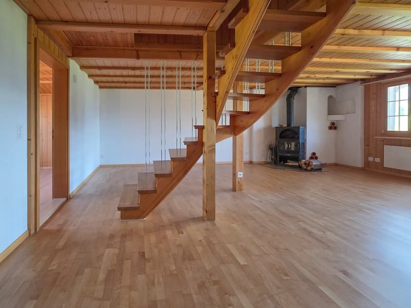 open room with wooden stairs, open fireplace, wooden floor