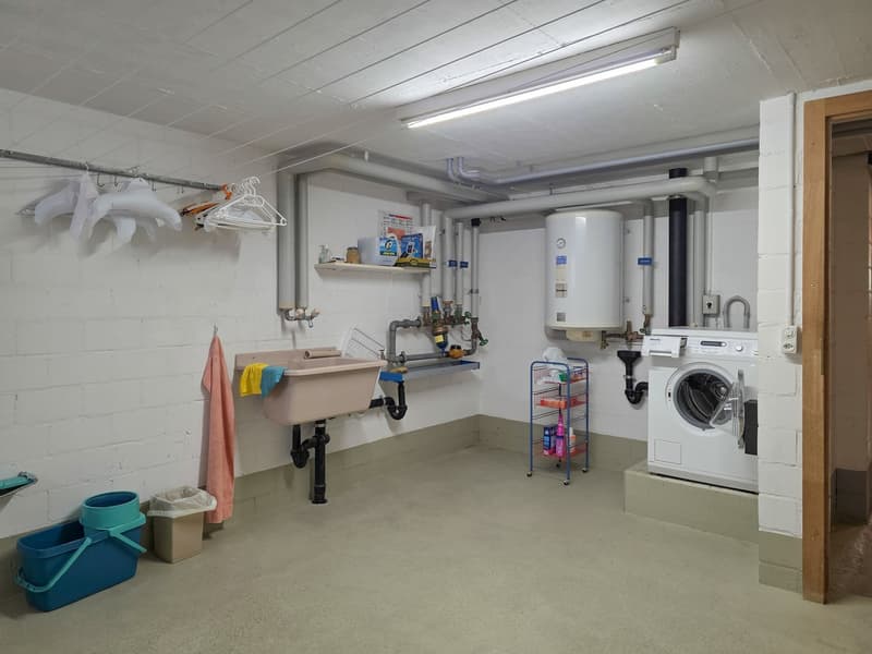 white walls, floor, washing machine, sink, shelves, storage rack, pipes, buckets, towel, laundry bag