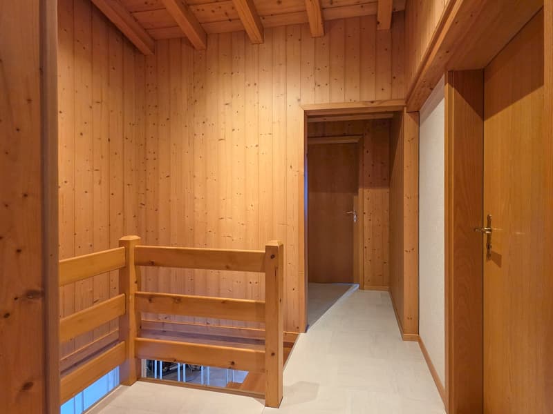 Hallway with wooden walls, wooden staircase, tiled floor, wooden handrail, two doors