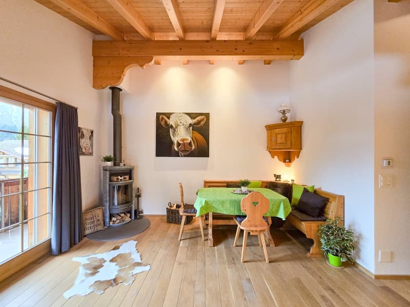 wooden floor, white walls, wooden ceiling, fireplace, dining table, wooden bench, green tablecloth, wooden chairs, potted plant, picture frame, wooden cabinet, lamp, rug, glass door, curtain