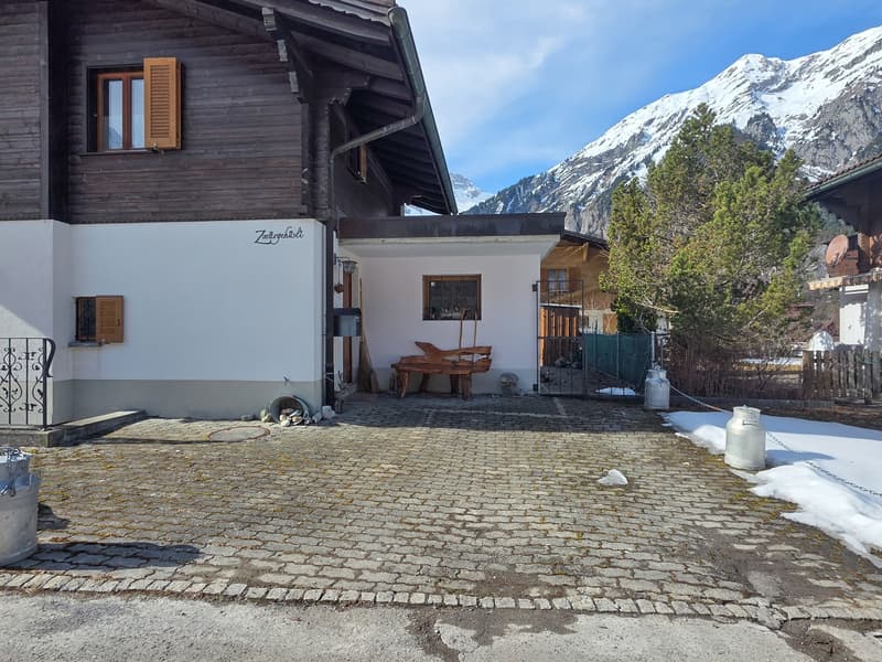 wooden exterior, white walls, wooden bench, snow, mountains in the background
