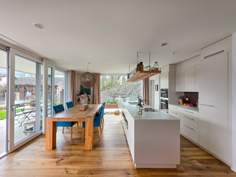 modern kitchen with dining area, wooden floor, large windows, sliding doors, dining table, blue chairs, kitchen island, white cabinets, modern appliances