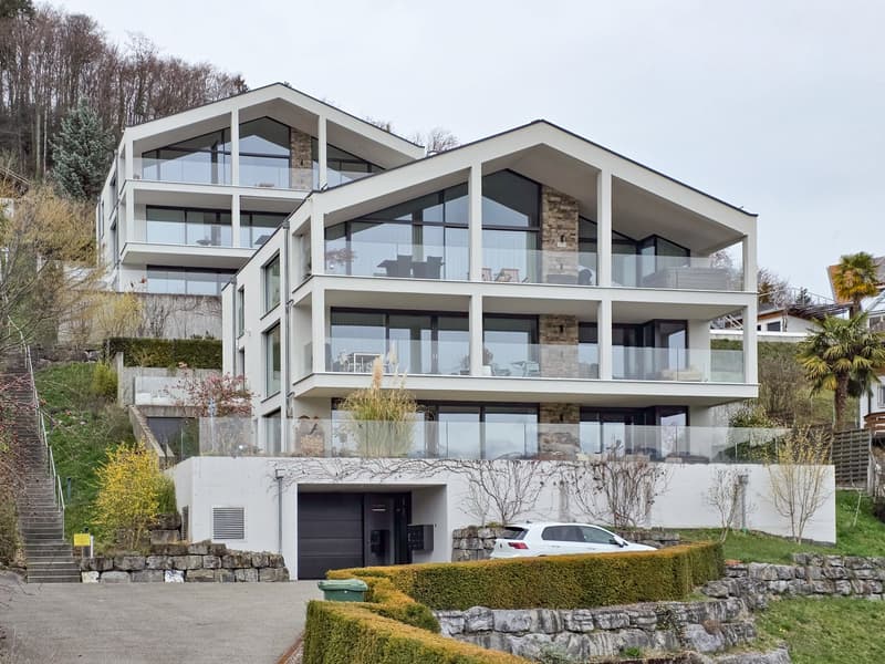 Modern 3-story house, white exterior, large glass windows, multiple balconies, garage, driveway, landscaped garden