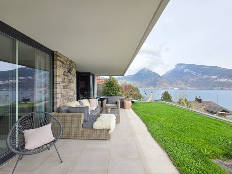 Outdoor terrace with a couch, chair, table, and a view of the lake and mountains
