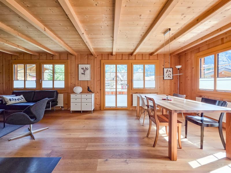 wooden walls, wooden floor, large windows, dining table, chairs, couch, side table, picture frames, lamp