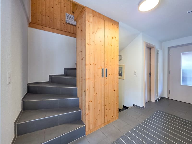 wooden staircase, wooden cabinet, tiled floor, white walls, ceiling light