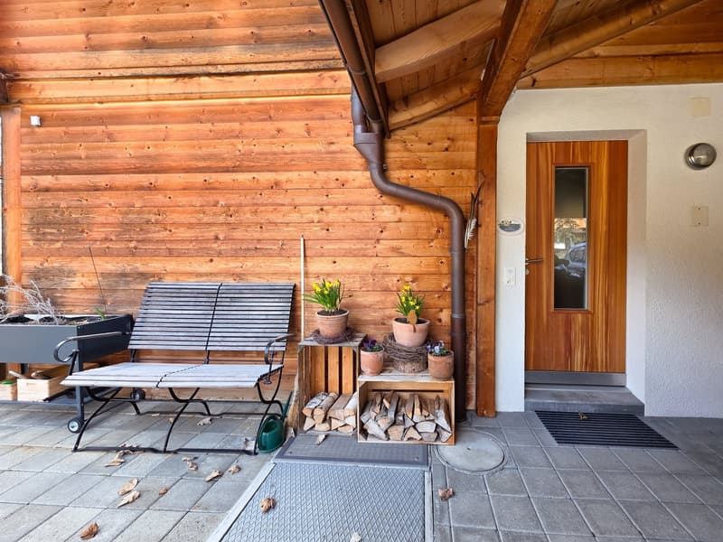 Wooden exterior wall, wooden bench, wooden storage boxes, potted plants, wooden door, tiled floor