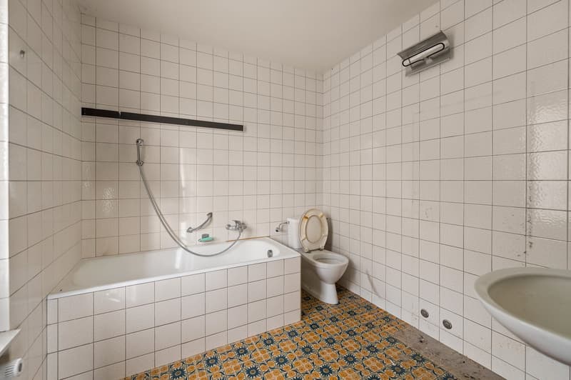 white tiled walls, bathtub, toilet, sink, showerhead, floor tiles