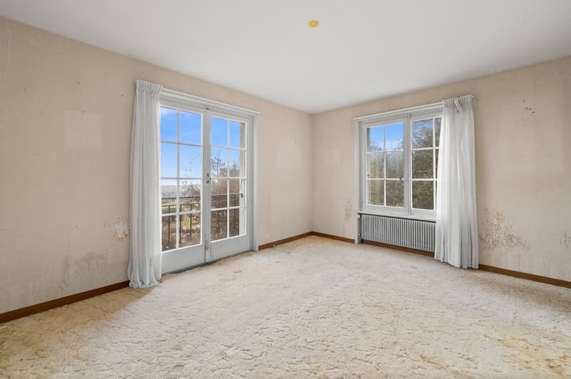 empty room, carpet floor, sliding doors leading to balcony, large windows, radiator